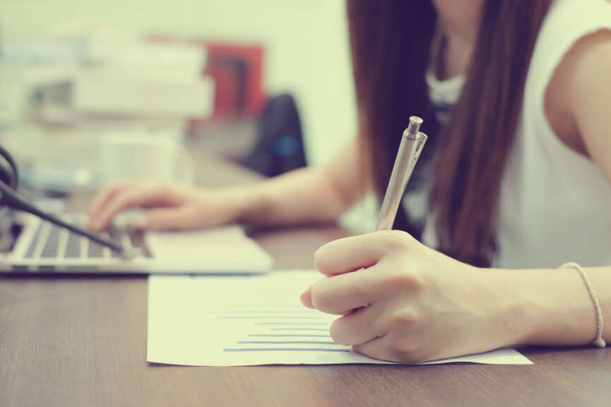 Close up of young girl writing on a paper, concept of writing skills improvement