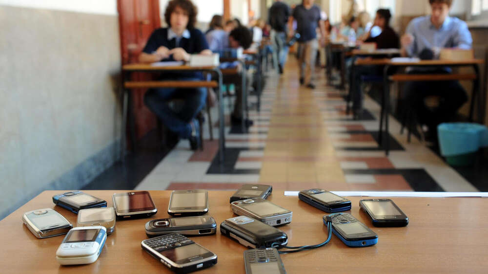 Prohibition for students to use a mobile phone during school lecture - mobile phones on a school desk, representing LA school's decision of cellphone ban